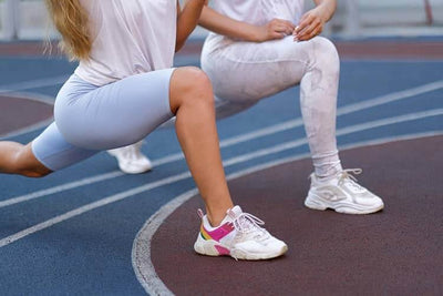 Dos atletas picsil fortaleciendo sus piernas con walking lunges o zancadas