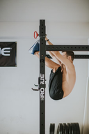 Atleta de lado haciendo toes to bar en un rack de crossfit